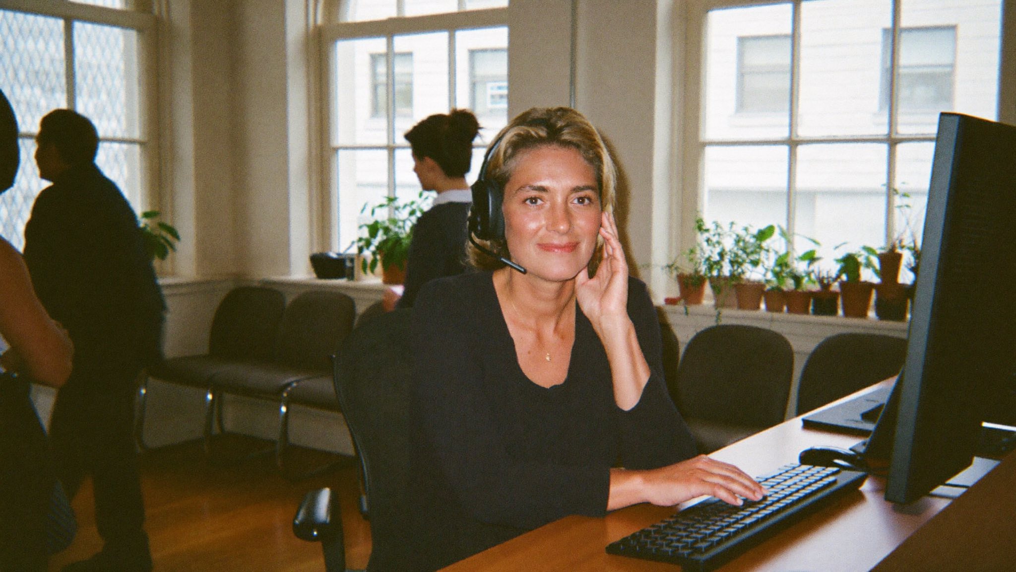 A receptionist with a headset answering calls in a bright office