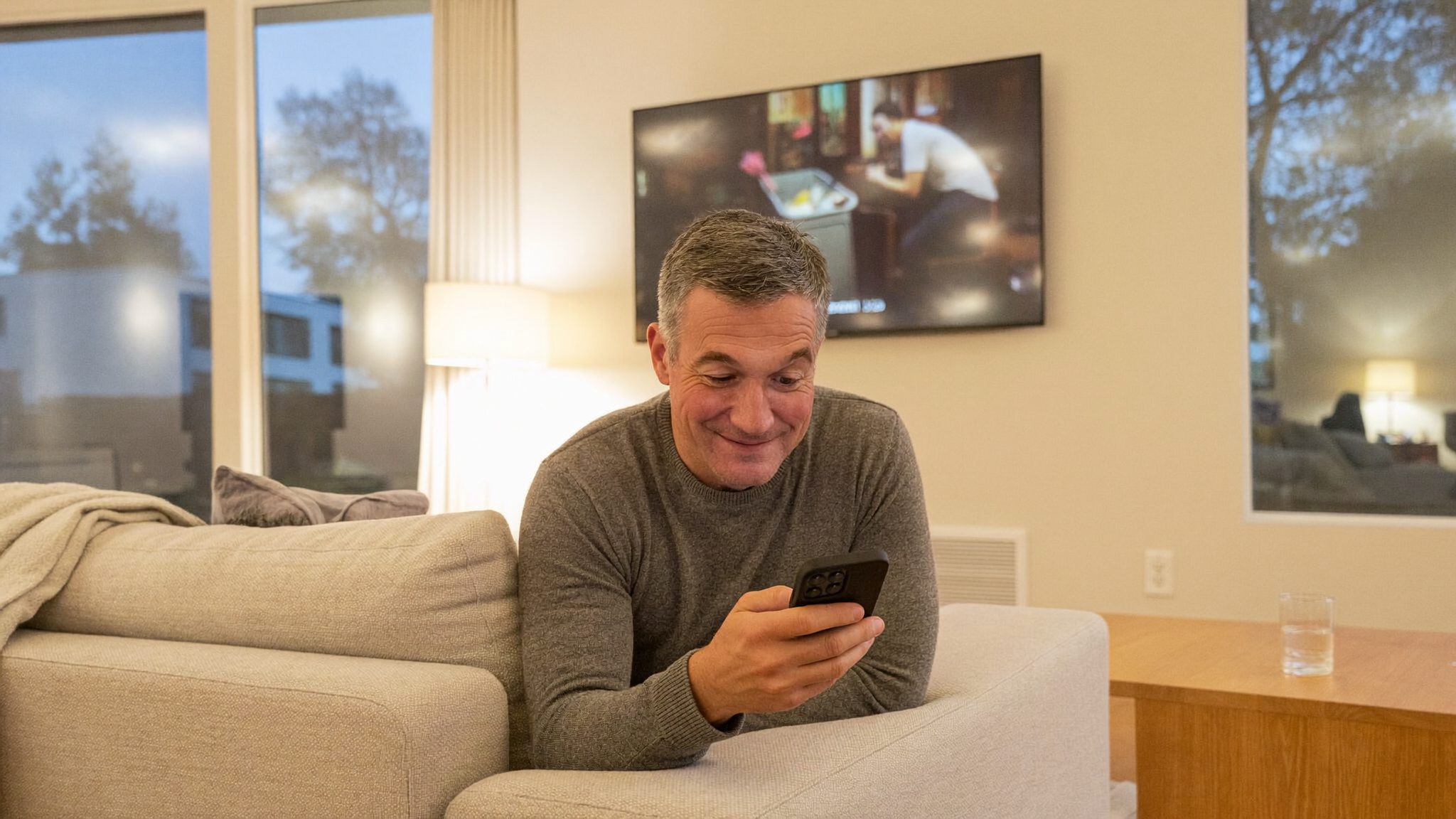 A man relaxed on the couch, sending the password from his phone with a small smile