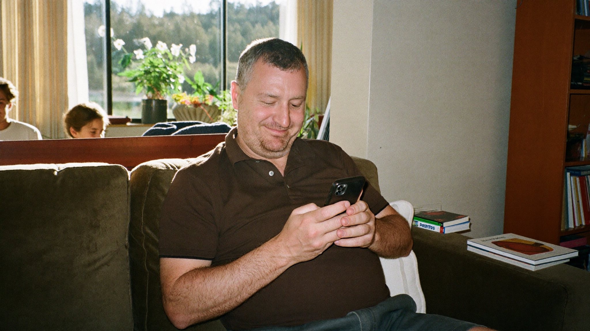 A man relaxed on the couch, sending the password from his phone with a small smile